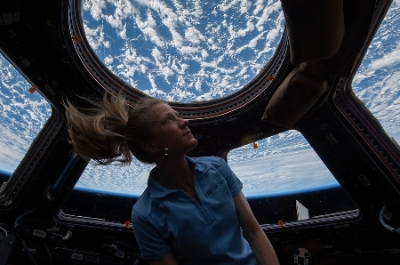 A female astronaut stares out the window at planet Earth